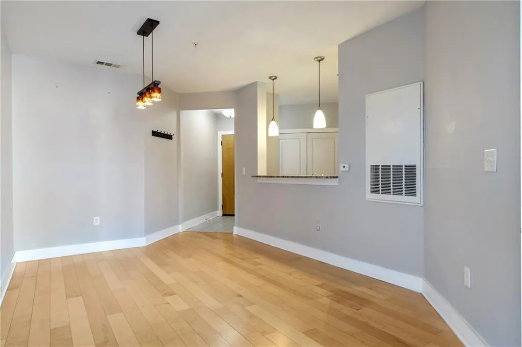 Empty room with light wood finished floors, visible vents, and baseboards