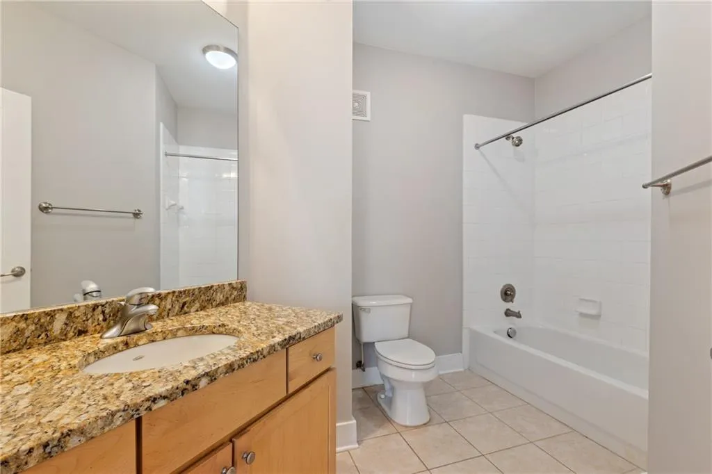 Bathroom featuring shower / tub combination, toilet, vanity, baseboards, and tile patterned floors