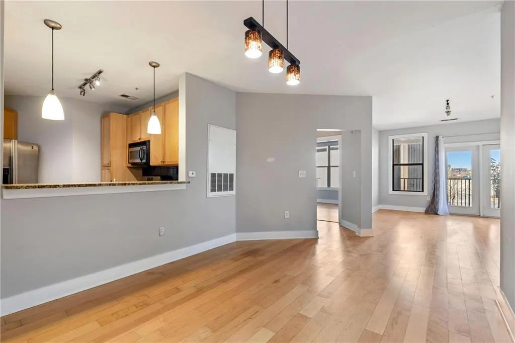 Unfurnished living room featuring light wood finished floors, rail lighting, visible vents, and baseboards