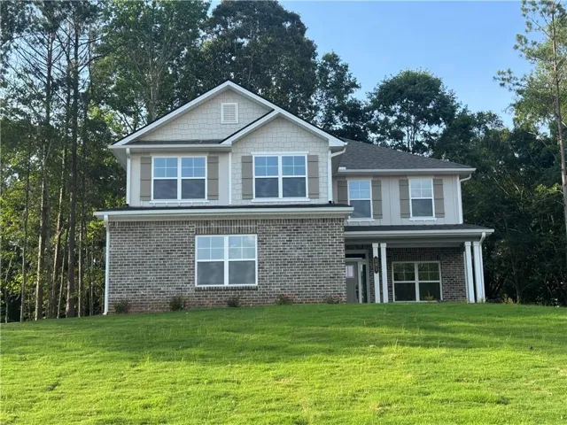 Two-story residence featuring a brick first level and shingle siding on the second level. 2-Car Side Entry Garage and large front yard.