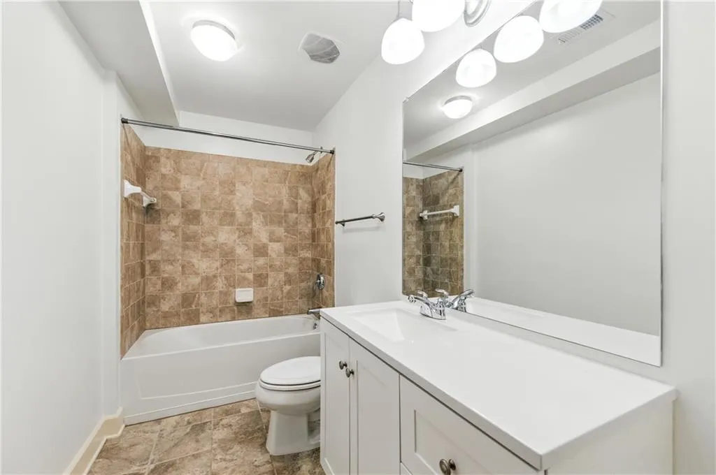 Bathroom with shower / washtub combination, vanity, and light stone finish flooring