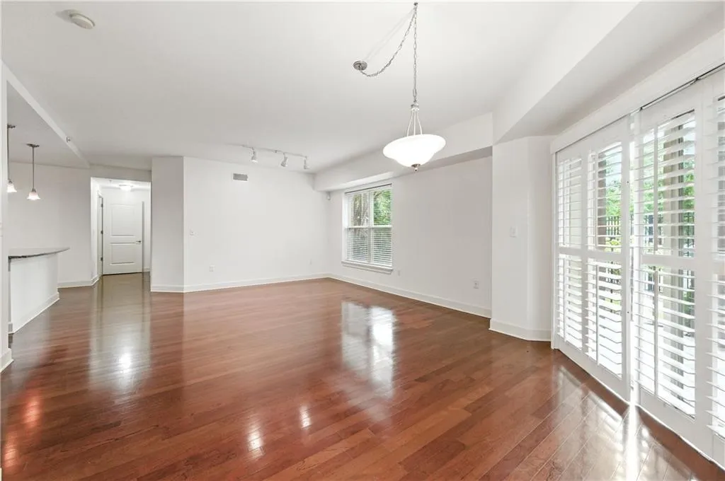 Unfurnished living room featuring dark wood-style flooring and rail lighting