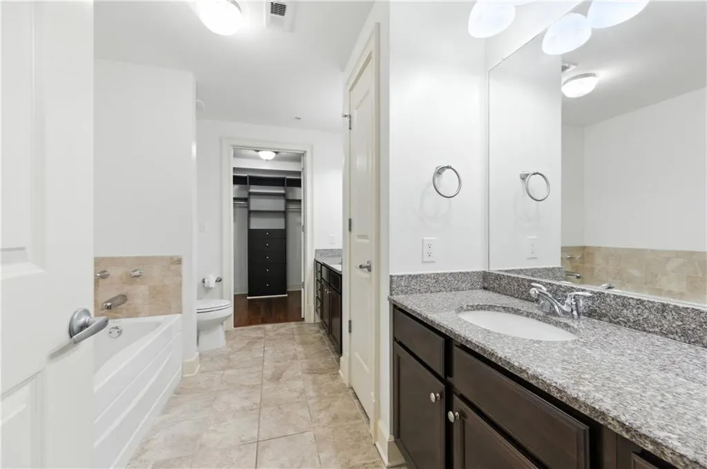 Full bath featuring vanity, a garden tub, light tile patterned floors, and a spacious closet