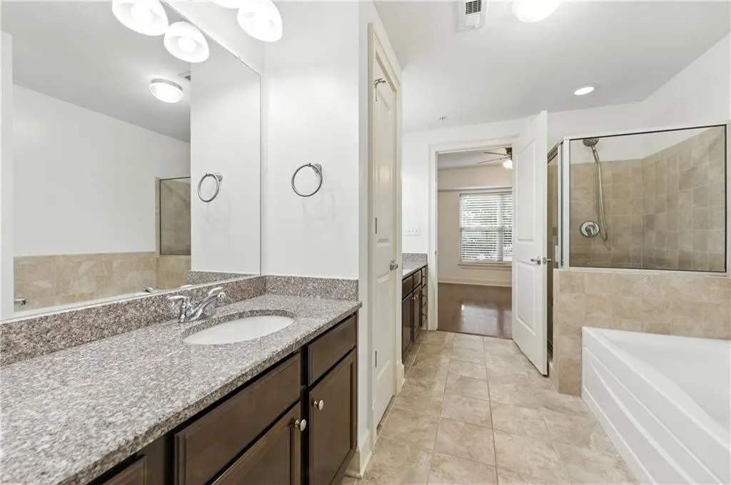 Bathroom featuring vanity, a bath, a stall shower, and light tile patterned floors