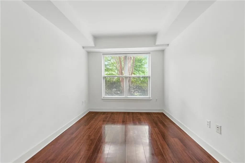 Empty room with dark wood-type flooring and baseboards