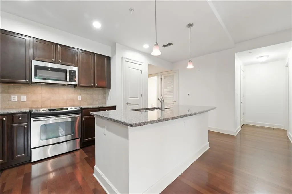 Kitchen with appliances with stainless steel finishes, tasteful backsplash, light stone counters, dark brown cabinets, and recessed lighting