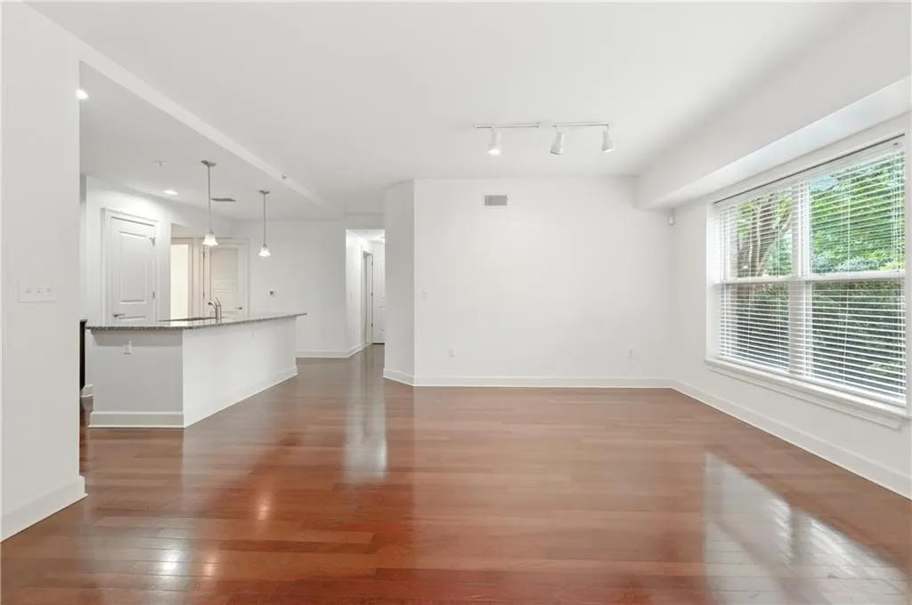Unfurnished living room featuring dark wood-type flooring and track lighting