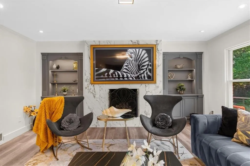 Living room featuring crown molding, wood finished floors, a premium fireplace, recessed lighting, and built in features