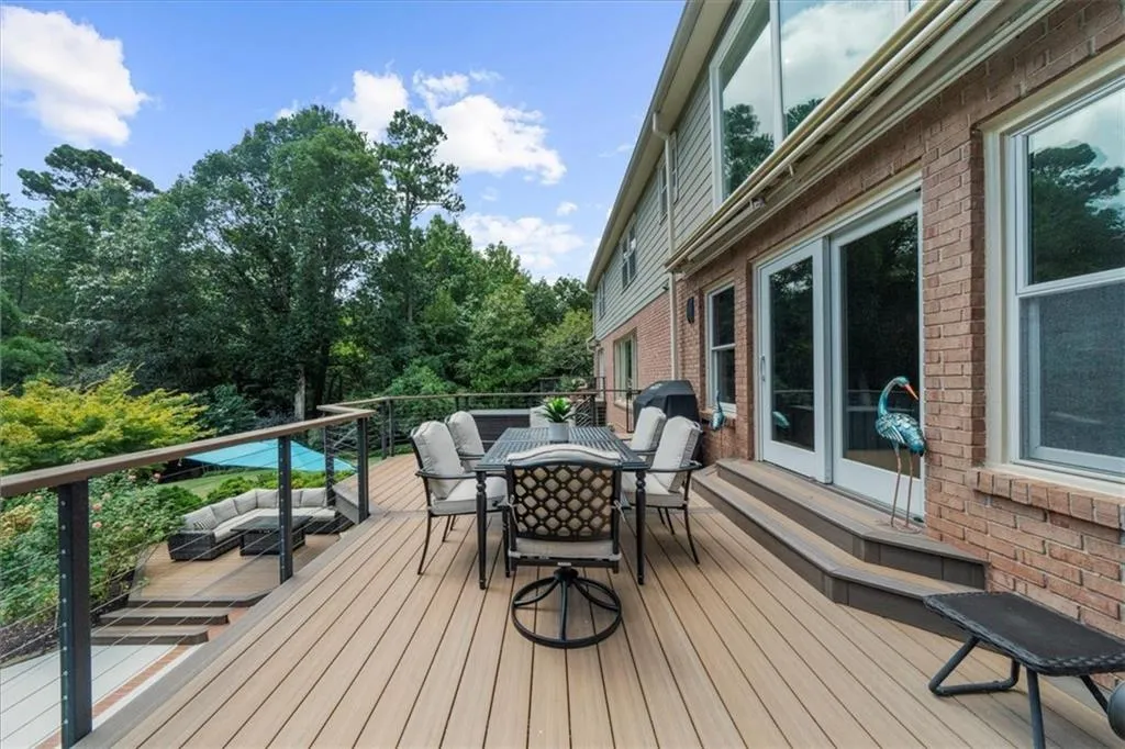 Wooden terrace featuring outdoor dining space, outdoor lounge area, view of wooded area, and entry steps