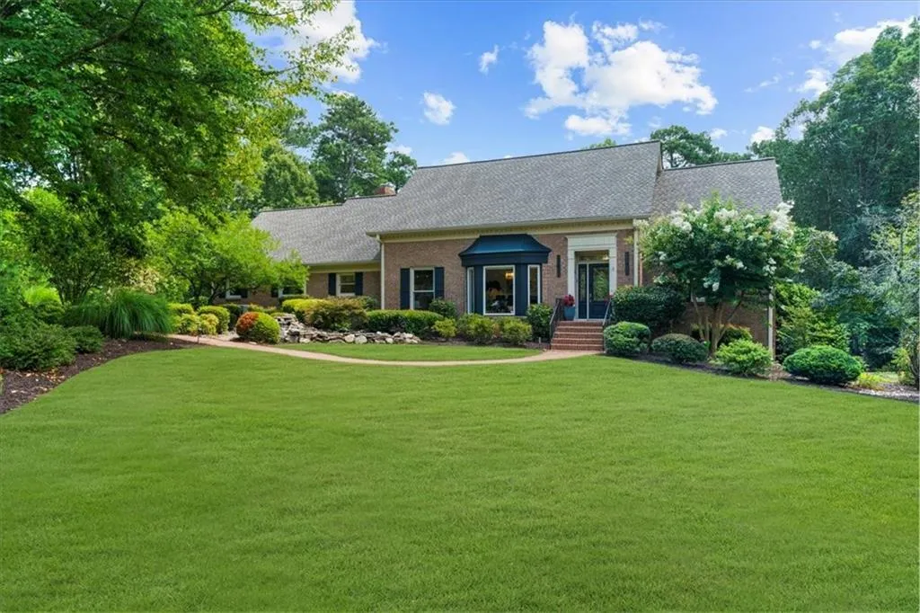 New england style home with a front yard, brick siding, and roof with shingles