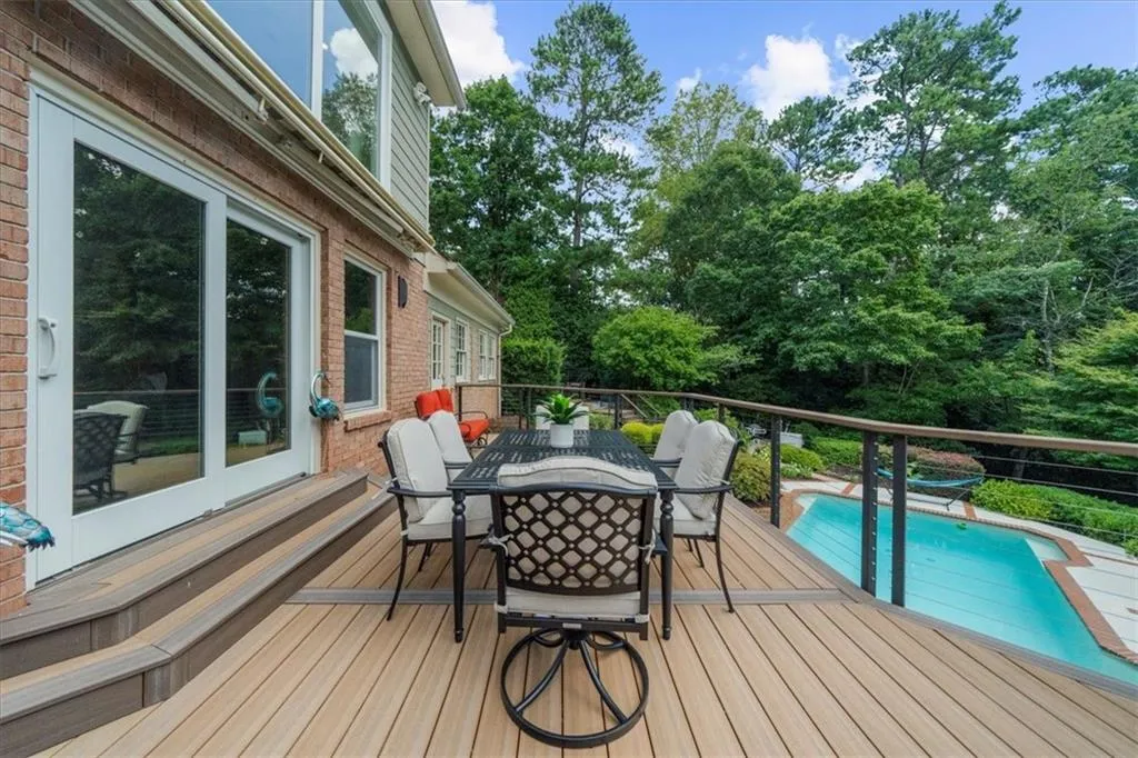Wooden deck with outdoor dining space and view of wooded area