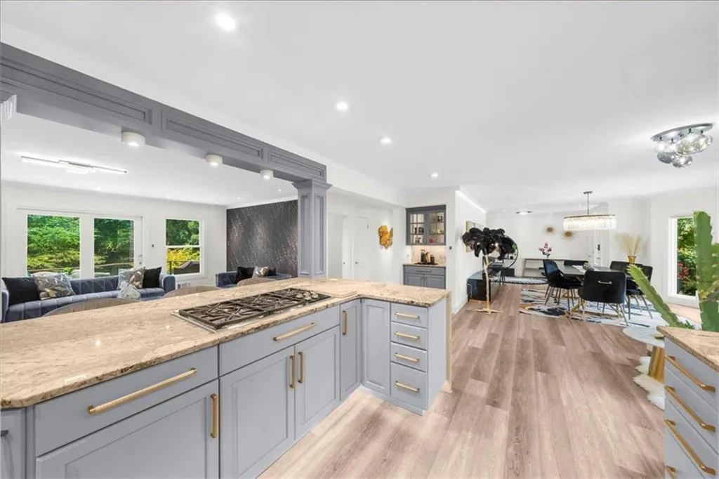 Kitchen with gray cabinets, open floor plan, light wood finished floors, stainless steel gas stovetop, and recessed lighting
