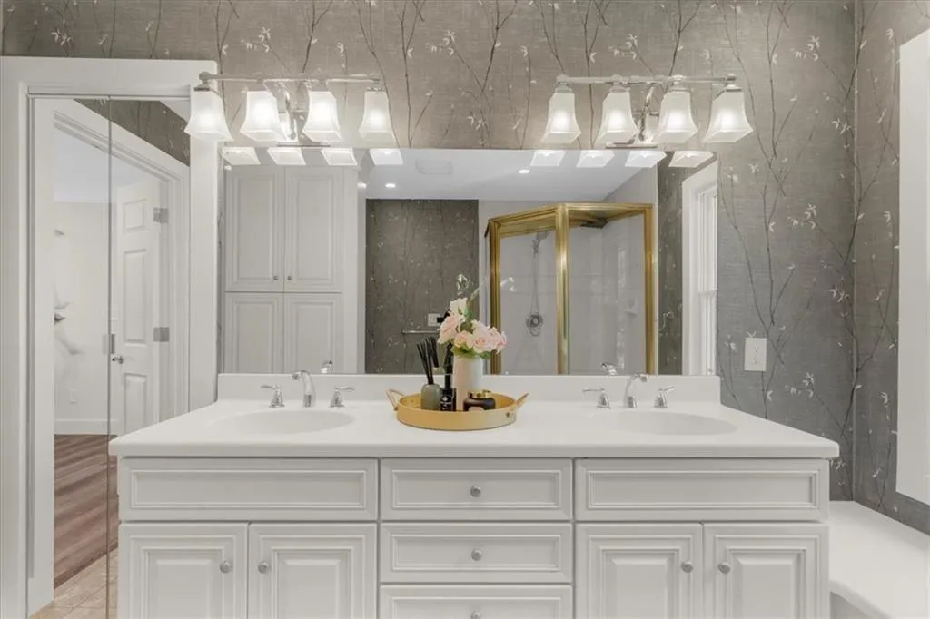 Full bathroom featuring double vanity and a stall shower