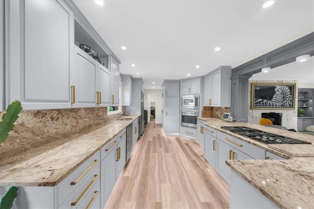 Kitchen featuring light stone countertops, backsplash, light wood finished floors, recessed lighting, and stainless steel appliances