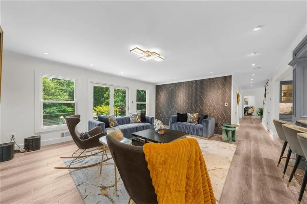 Living area with recessed lighting, an accent wall, light wood finished floors, and crown molding