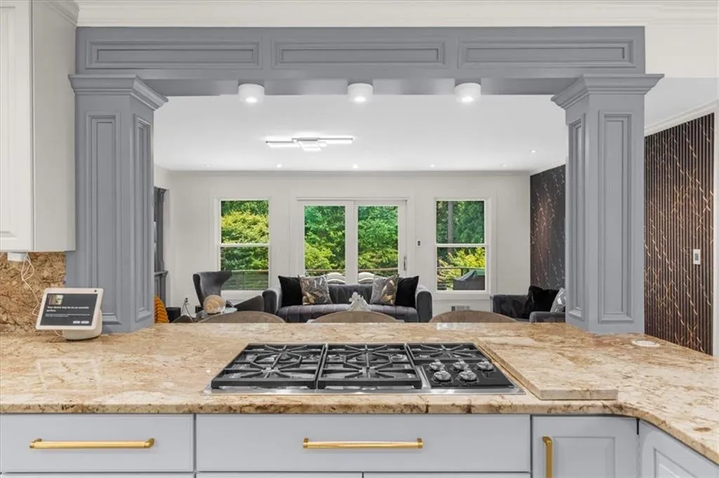 Kitchen with open floor plan, stainless steel gas cooktop, ornate columns, crown molding, and tasteful backsplash