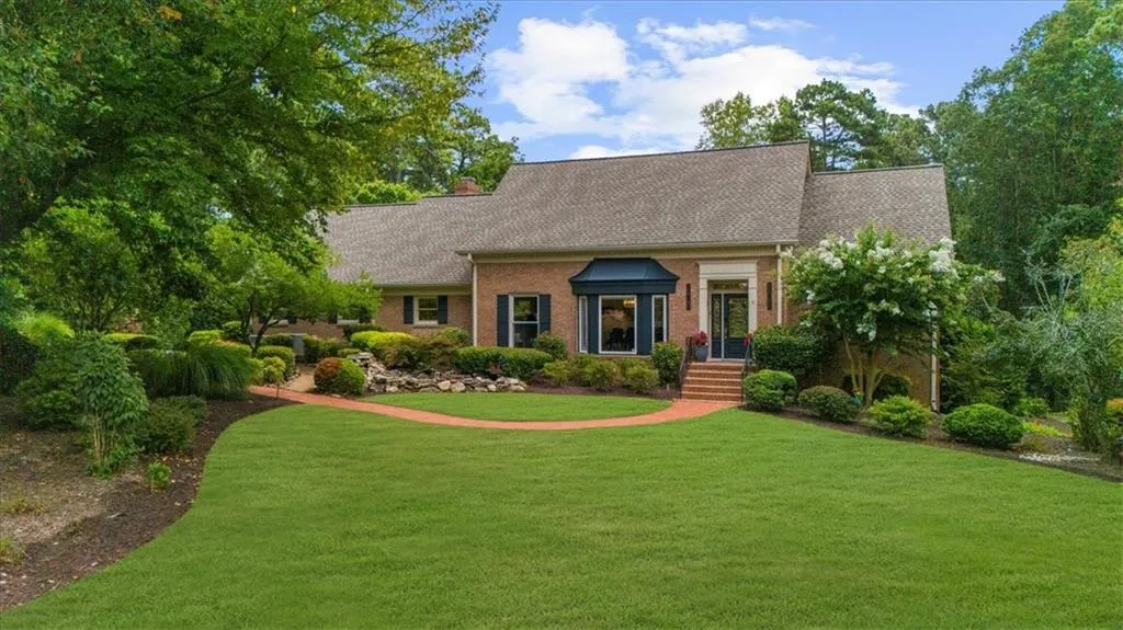 Cape cod home featuring a front lawn, brick siding, roof with shingles, and a chimney