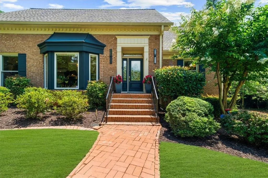 View of exterior entry with brick siding, a yard, and roof with shingles