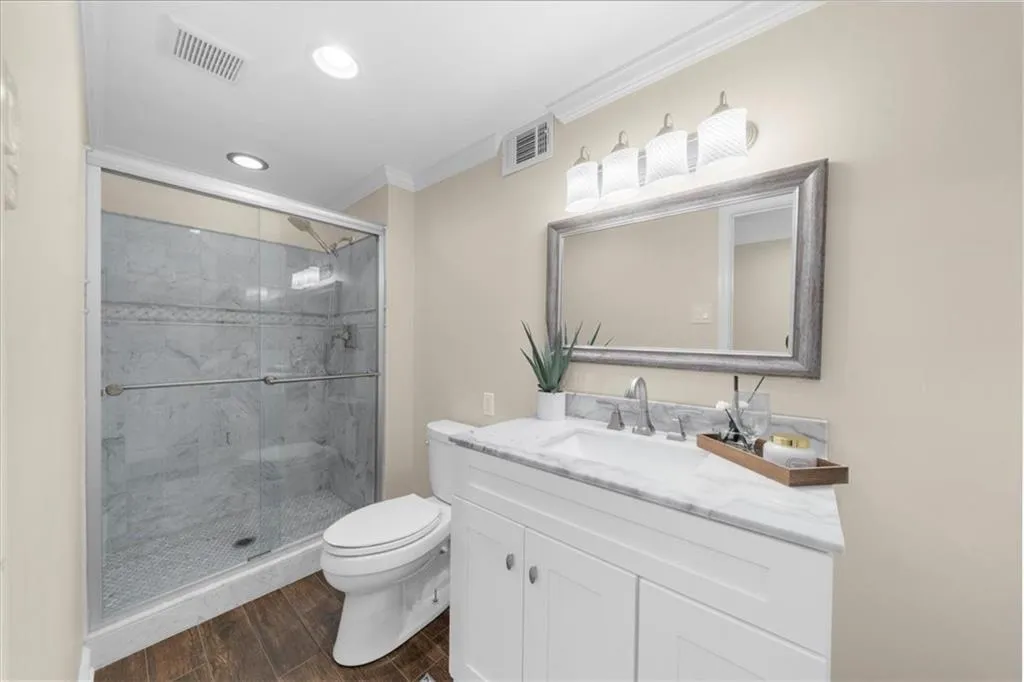 Full bathroom featuring ornamental molding, vanity, a stall shower, wood finished floors, and recessed lighting