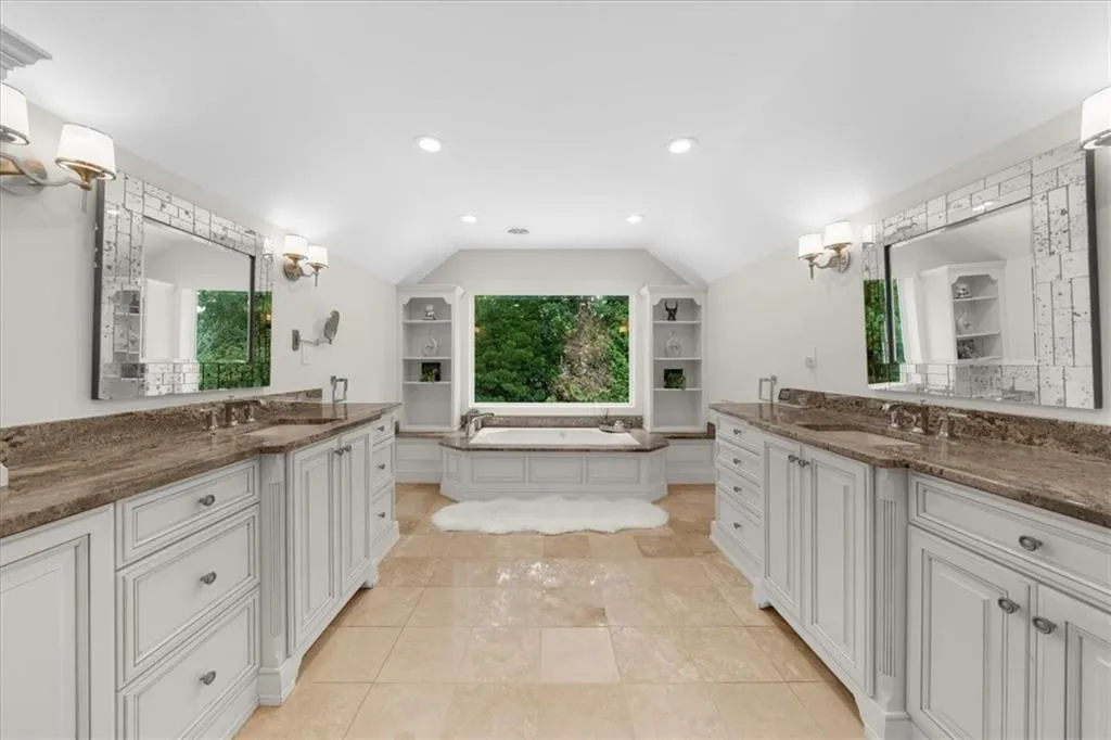Full bath with two vanities, vaulted ceiling, a bath, and recessed lighting