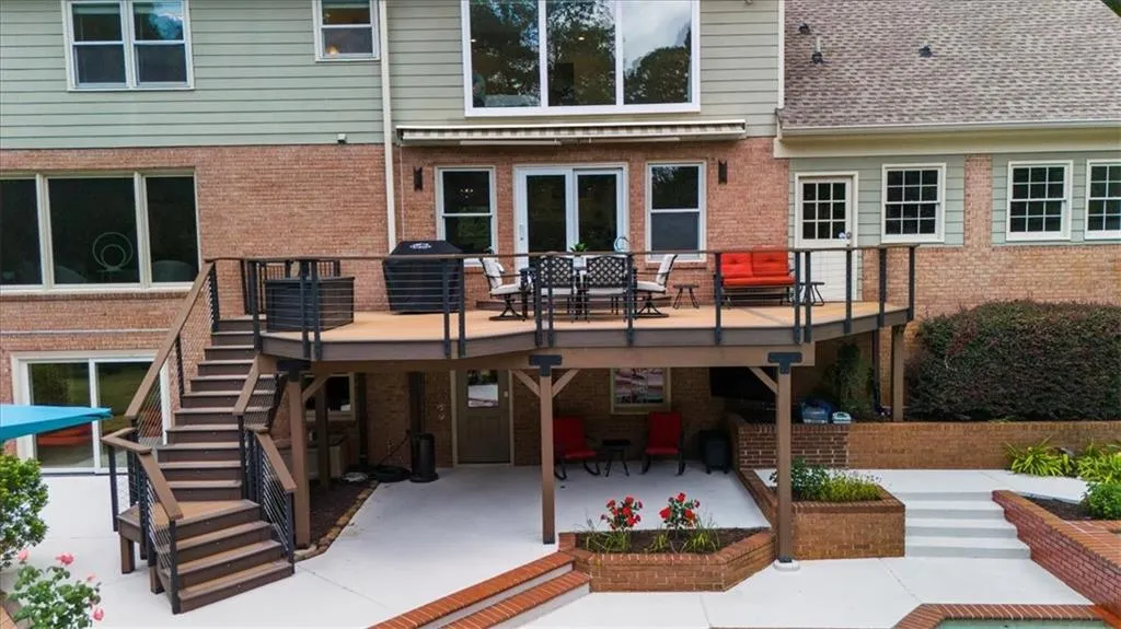 Rear view of property featuring stairs, a patio area, a deck, outdoor dining space, and brick siding