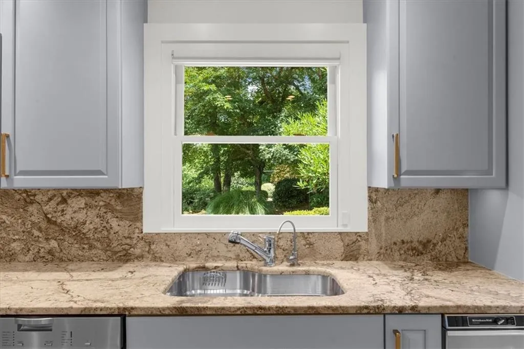 Kitchen with tasteful backsplash, light stone countertops, and dishwasher