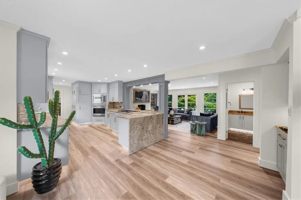Kitchen featuring gray cabinetry, light wood-style flooring, ornate columns, open floor plan, and recessed lighting