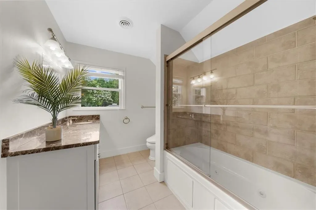 Bathroom with tile patterned floors, vanity, and a combined bath / shower with jetted tub
