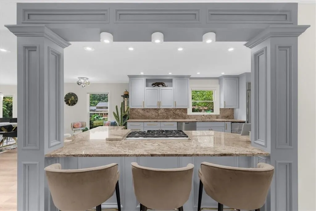 Kitchen with recessed lighting, open shelves, a kitchen bar, tasteful backsplash, and light stone counters