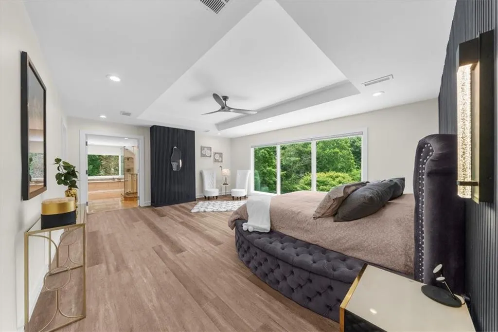 Bedroom featuring a tray ceiling, wood finished floors, recessed lighting, connected bathroom, and ceiling fan