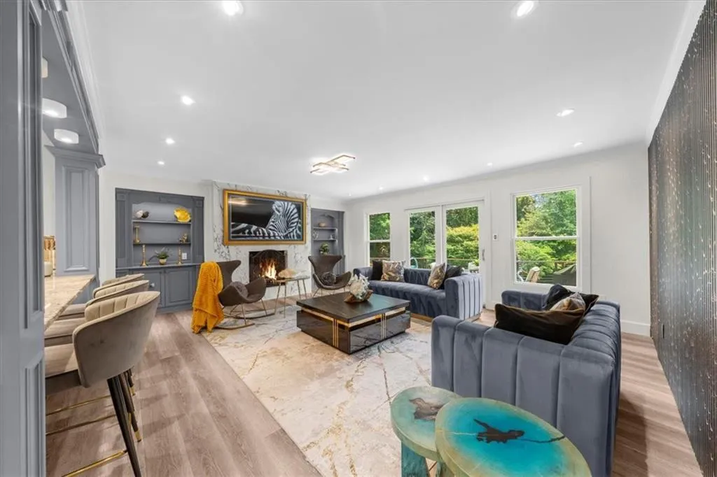 Living area featuring light wood finished floors, a warm lit fireplace, built in features, and recessed lighting