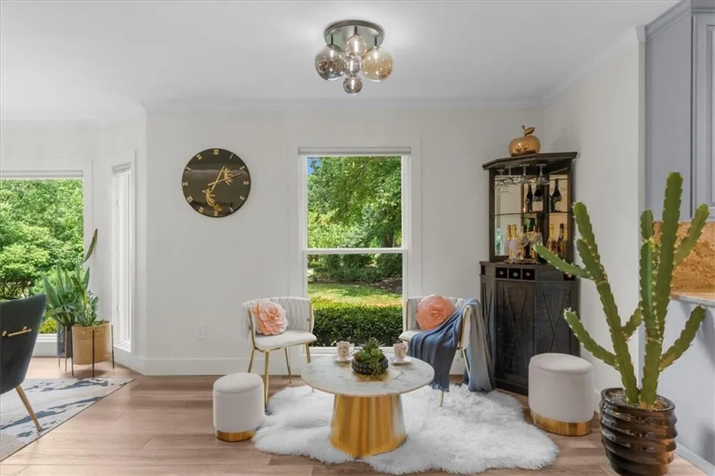 Sitting room with healthy amount of natural light, wood finished floors, ornamental molding, and a chandelier