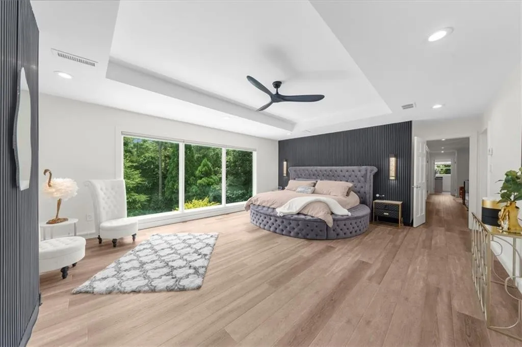 Bedroom with a raised ceiling, recessed lighting, wood finished floors, and a ceiling fan