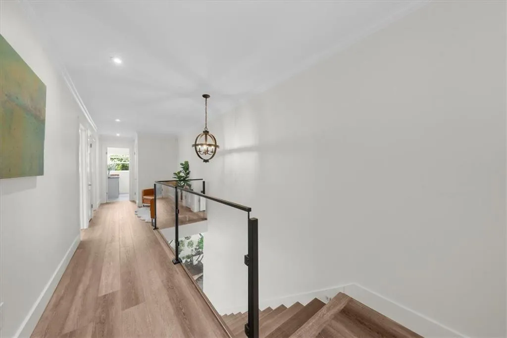 Hall with an upstairs landing, crown molding, a chandelier, light wood finished floors, and recessed lighting