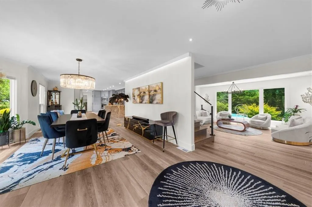 Dining area featuring healthy amount of natural light, a chandelier, crown molding, wood finished floors, and stairs