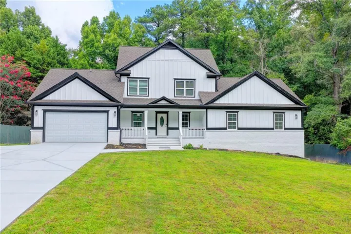 Striking two-story Colonial featuring a crisp white and black exterior with multiple peaked rooflines and dormers