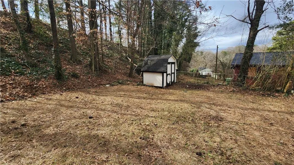 View of yard featuring a storage unit, an outdoor structure, and fence
