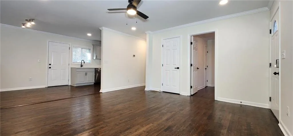 Unfurnished living room featuring baseboards, dark wood finished floors, a sink, and recessed lighting