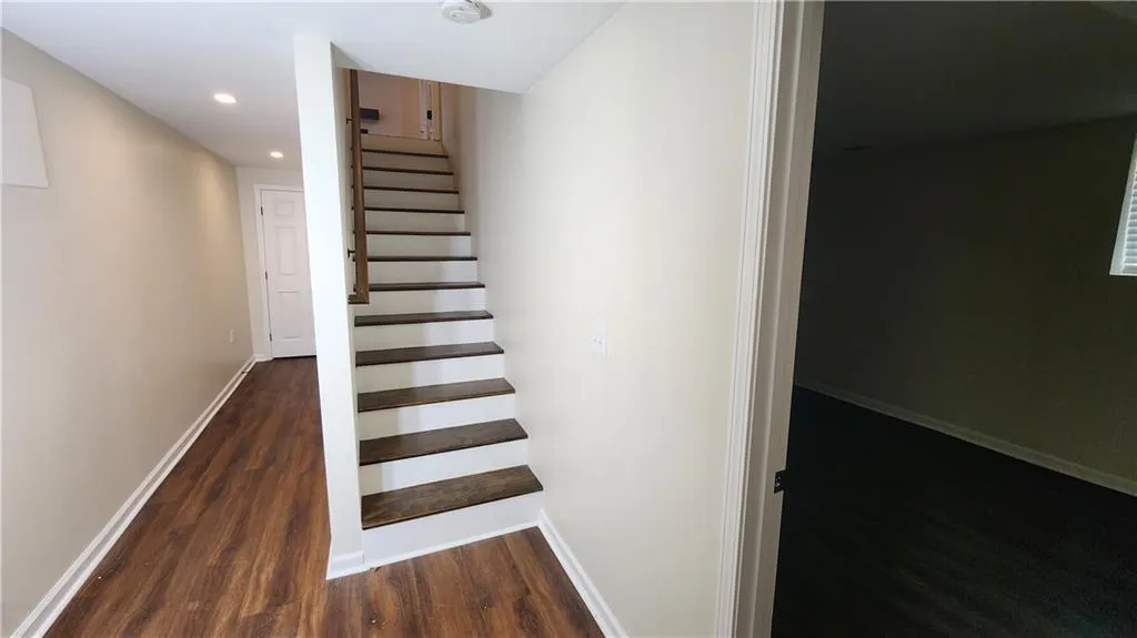 Stairway with baseboards, wood finished floors, and recessed lighting
