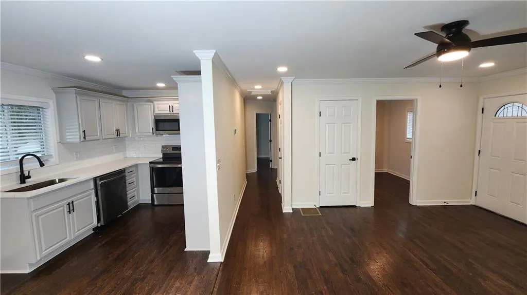 Kitchen featuring appliances with stainless steel finishes, dark wood-style flooring, light countertops, and a sink