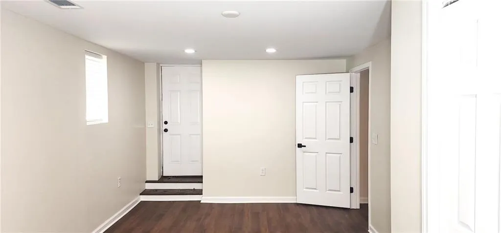Corridor featuring visible vents, baseboards, dark wood-type flooring, and recessed lighting