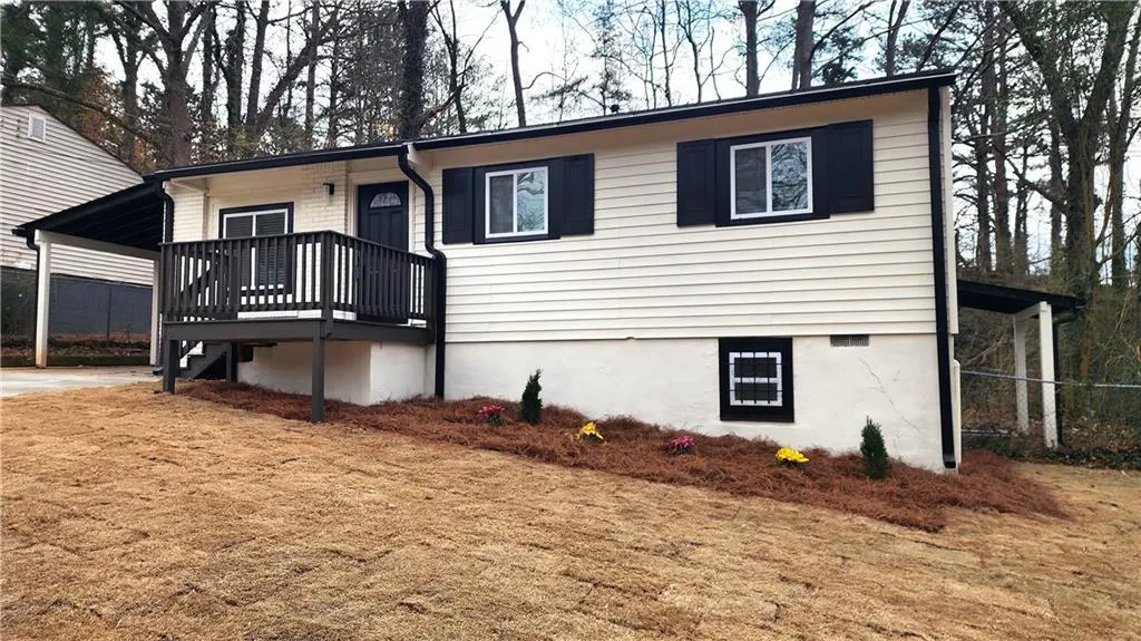 View of front facade with a carport and a wooden deck