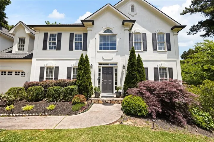 White stucco exterior with black shutters and a dark entry door