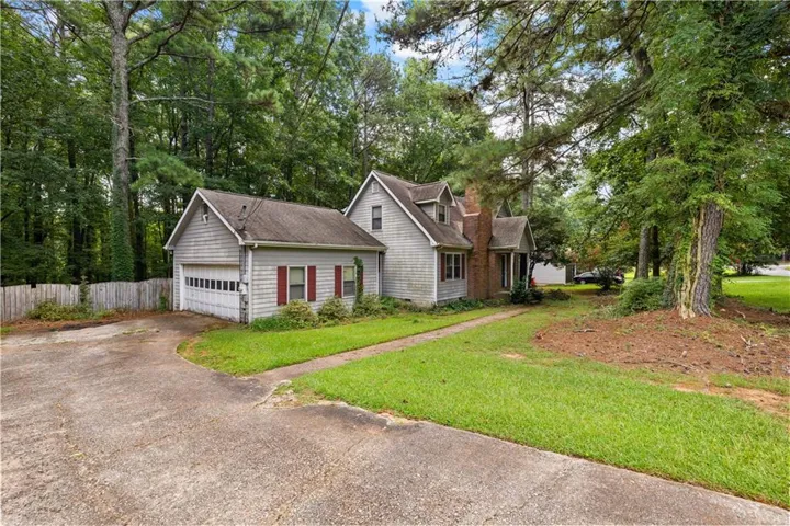 Detached garage with horizontal siding and a panel garage door, brick chimney exterior, and a concrete driveway
