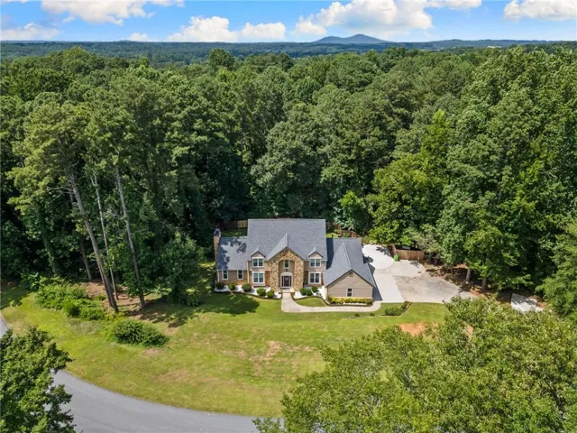 Traditional-style residence featuring a prominent stone facade, a multi-gabled roofline, and an integrated garage