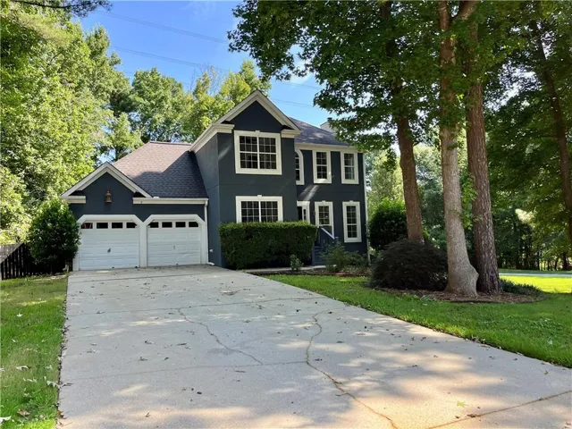 Two-story residence featuring a two-car garage, dark-toned exterior siding with white trim, and a paved driveway