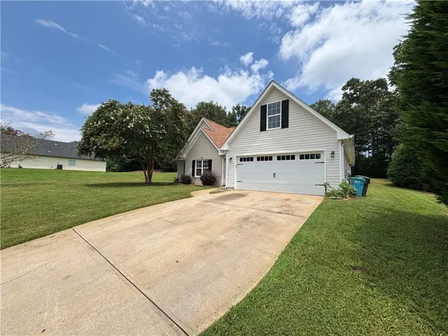 Exterior featuring light-colored siding, a gabled roofline, and a concrete driveway