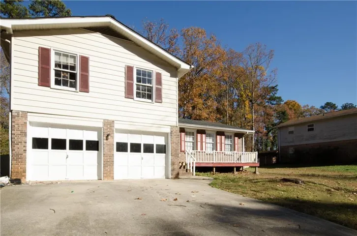Tri-level home with a front lawn, brick siding, a garage, and driveway