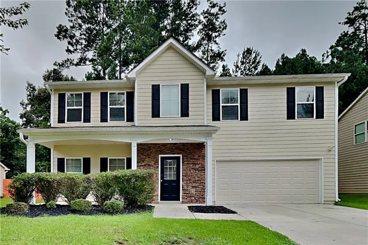 Two-story residence featuring light-colored siding and a covered front porch with white columns
