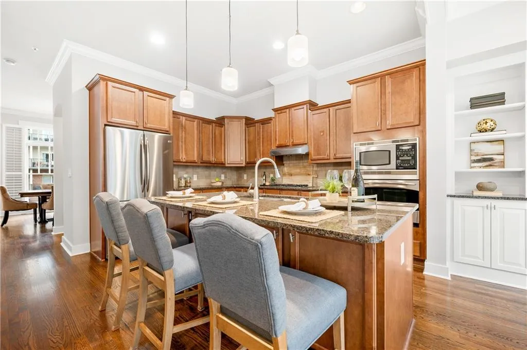 Kitchen with a kitchen bar, dark stone counters, wood finish cabinets, a kitchen island with sink, and decorative light fixtures